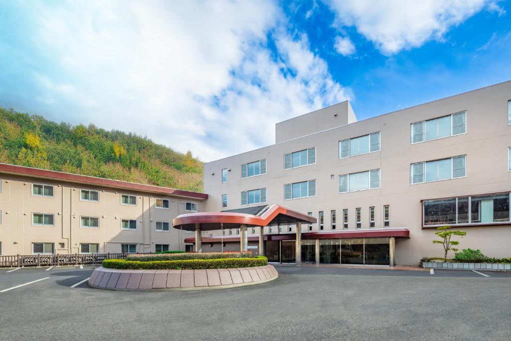 小樽朝里川温泉ホテル的一座白色的大建筑,背景是一座山