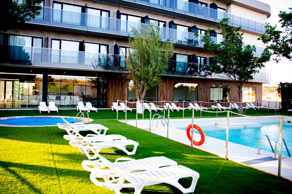 JorqueraHotel Spa Mirador的一座带白色草坪椅和游泳池的游泳池的建筑