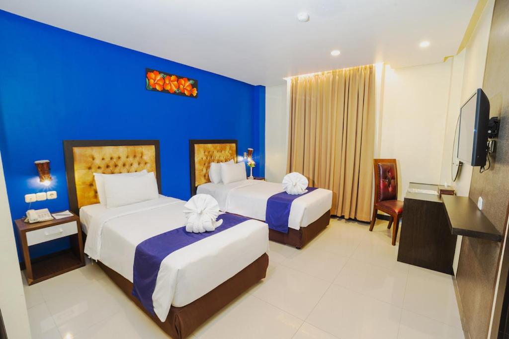 查亚普拉Parkside Star Hotel Jayapura的酒店客房设有两张床和蓝色的墙壁。