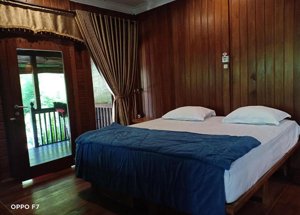 PasanggaranRumah Mertua Pulau Merah的一间卧室配有一张带木墙的大床