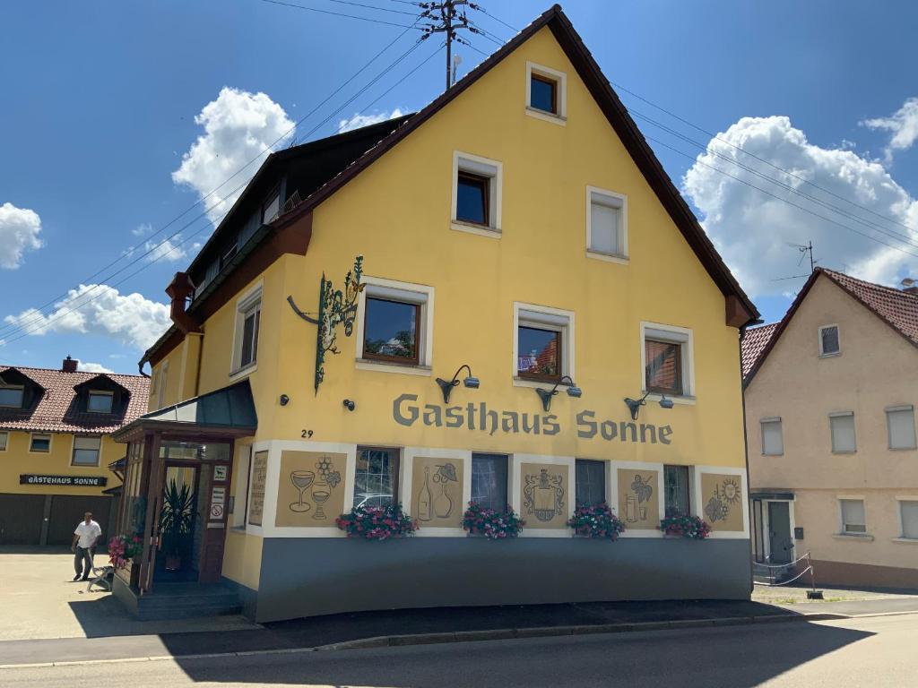HohenstadtGasthaus Sonne的黄色的建筑,旁边标有标志
