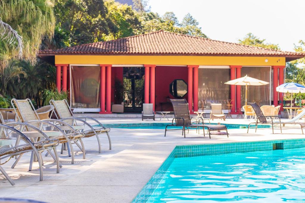 伊泰帕瓦Bomtempo II Chales by Castelo Itaipava的一个带椅子和遮阳伞的游泳池的度假酒店