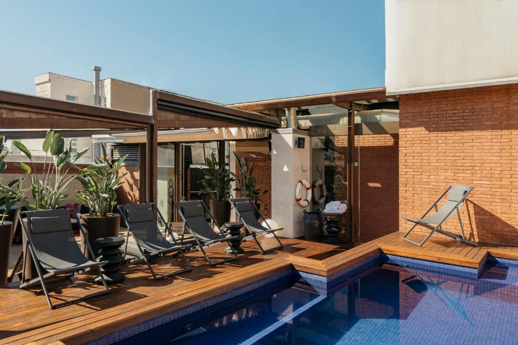 巴塞罗那Hotel Granados 83, a Member of Design Hotels的一组椅子坐在泳池旁的甲板上