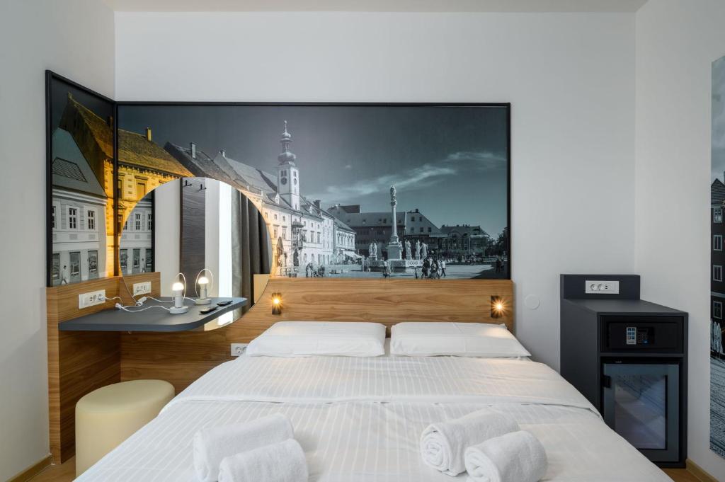 马里博尔B&B Hotel Maribor的卧室配有白色大床和壁画