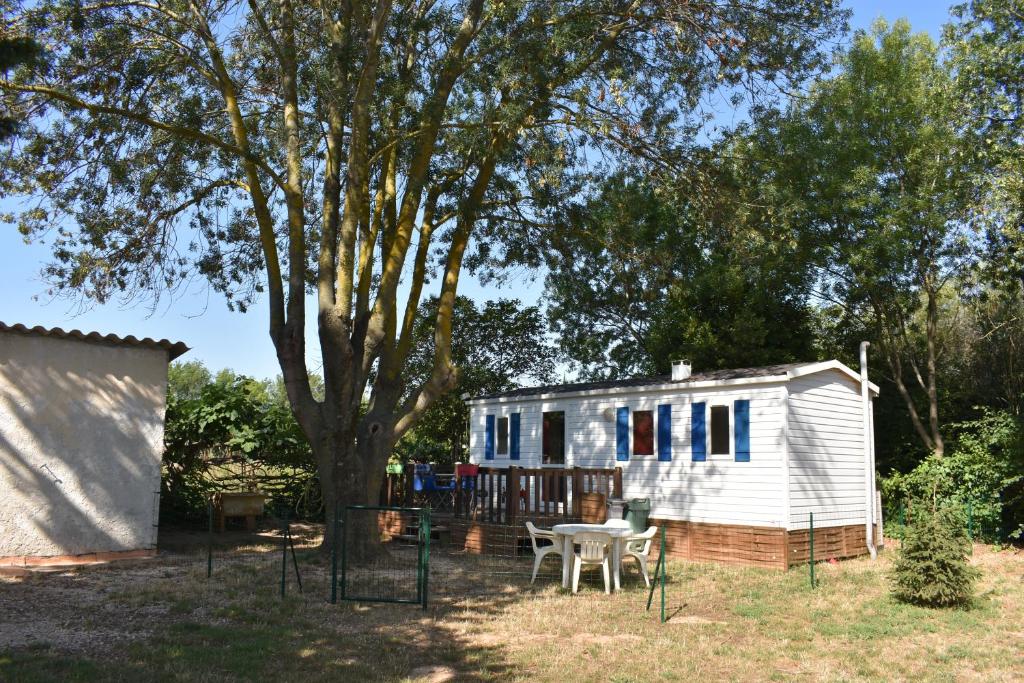 耶尔mobil-home sur terrain bucolique的一个小房子,有桌子和一棵树