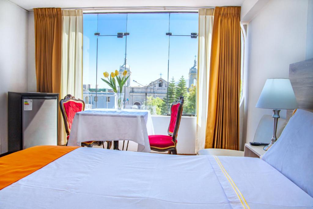 阿雷基帕Hotel Plaza San Antonio Arequipa的酒店客房带一张床、一张桌子和椅子
