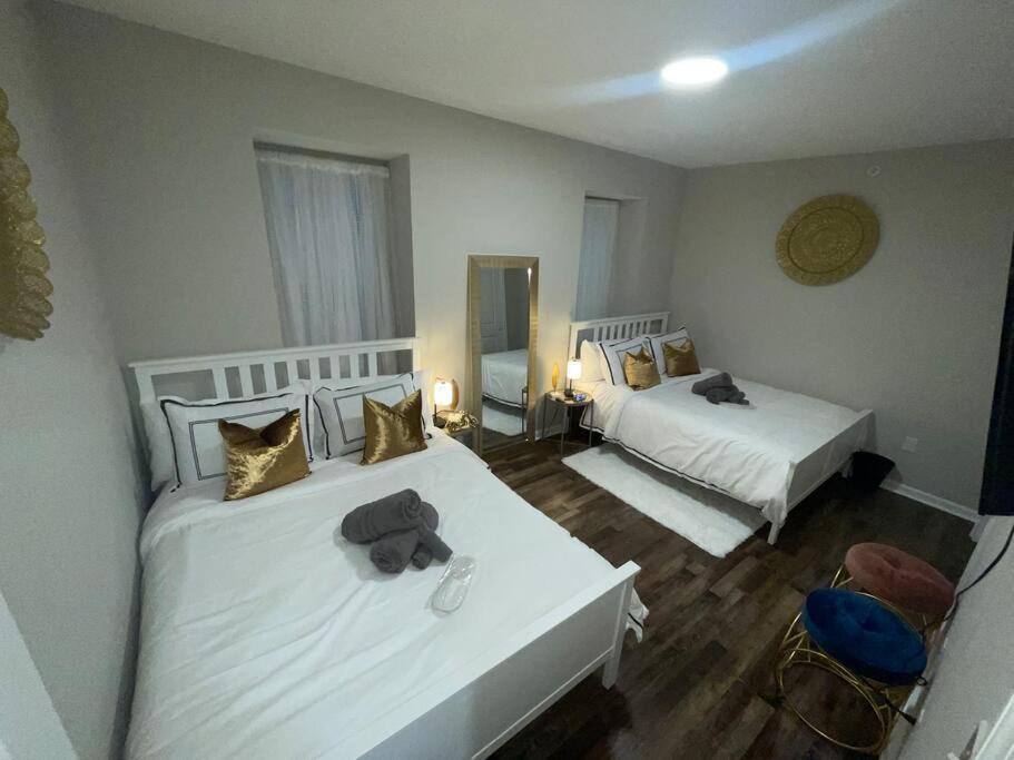费城THE ROOFTOP OASIS的一间卧室配有两张带白色床单和金色枕头的床。