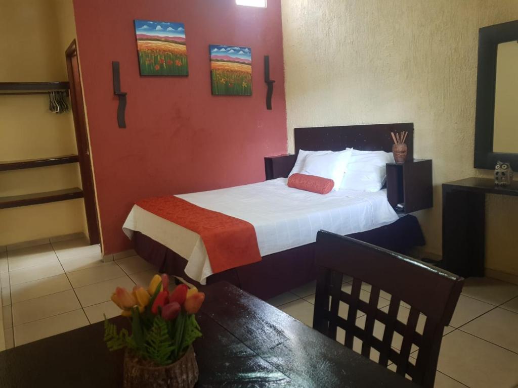 Nueva San SalvadorEl Patio de Don Moncho的配有床和鲜花桌的酒店客房