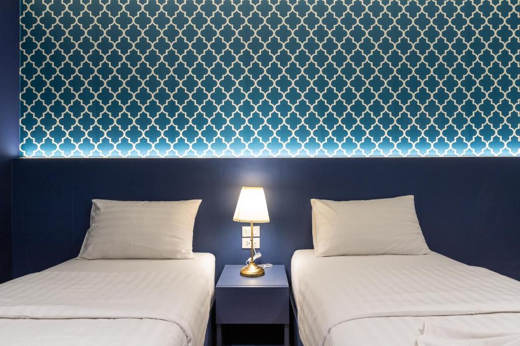 曼谷暹罗之星酒店的客房设有两张床和一张带台灯的桌子。