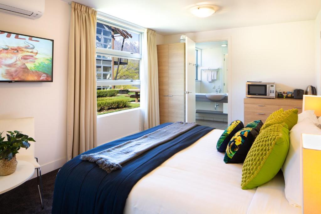 皇后镇QS Marina的卧室配有带枕头的床铺和窗户。