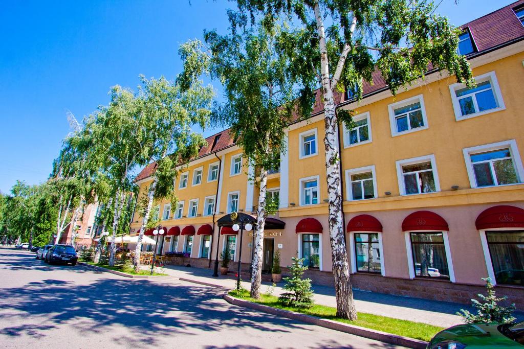 斯捷尔利塔马克Grand Hotel Vostok的街道前方有树木的黄色建筑