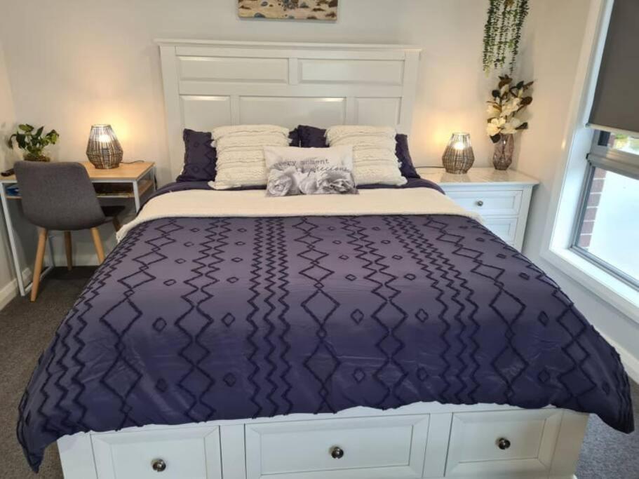温耶德Kadi House - Unit 1的卧室内的一张带紫色棉被的床