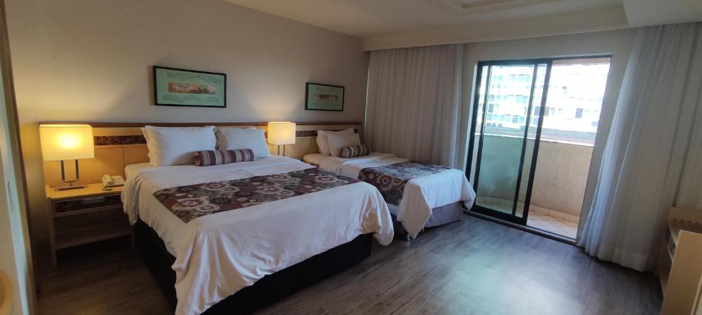 巴西利亚FLAT DE ALTO PADRÃO - ENORME - CENTRO DA CIDADE - 2 Camas - 1 Queen e 1 Solteiro - Arrumação Diária Gratuita - Excelente Atendimento - VARANDA - COZINHA的酒店客房设有两张床和一个阳台。