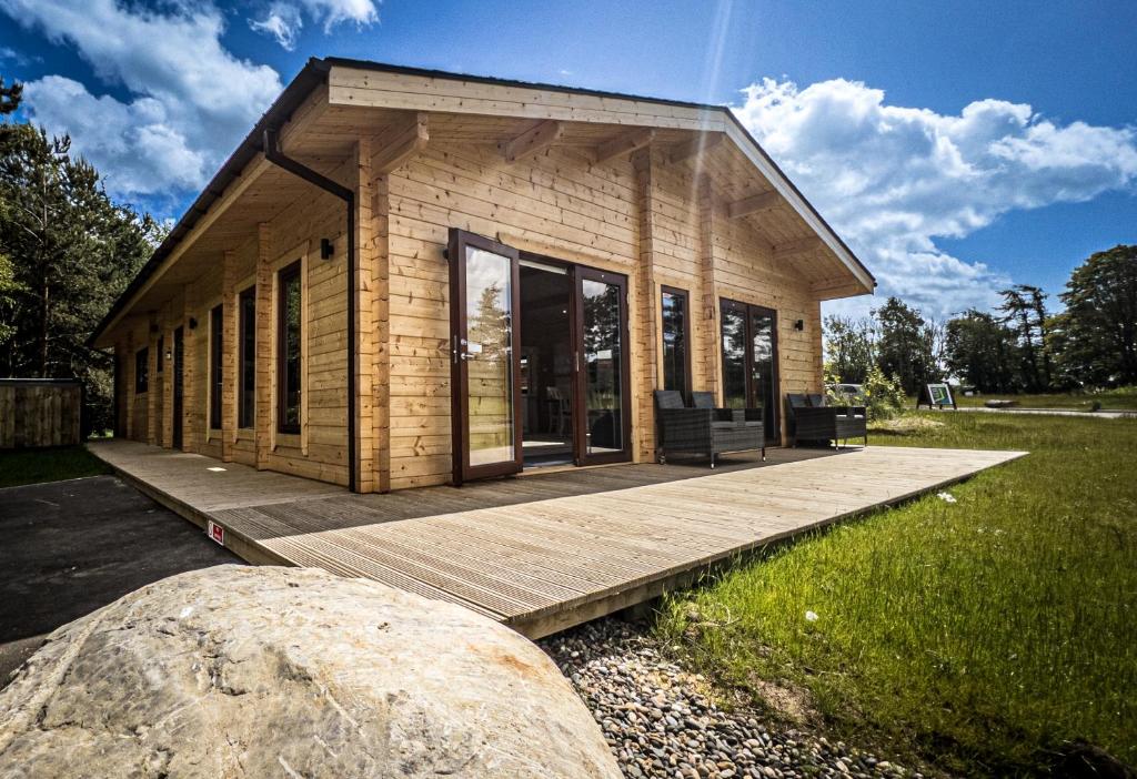 莫珀斯Sundance Lodge, Fantastic New Cabin with Hot Tub - Sleeps 6 - Largest In Felmoor Park的木制甲板上的一个小房子,上面有大岩石