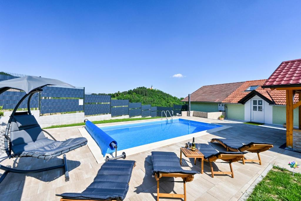 PregradaKuća za odmor Tranquilo的一个带椅子和遮阳伞的游泳池以及一间房屋