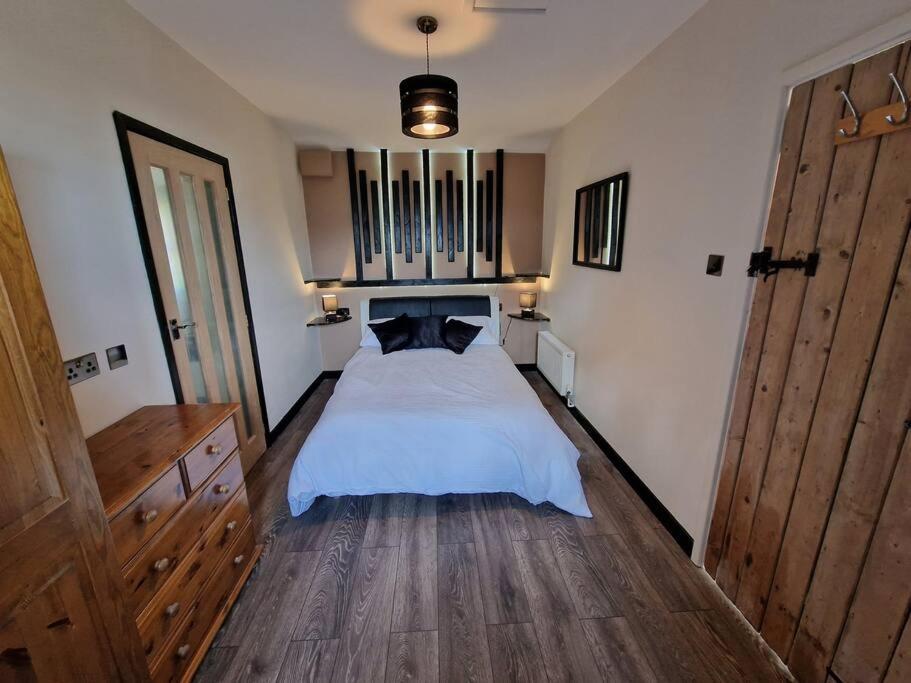 阿伯加文尼Swallows Nest的卧室铺有木地板,配有白色的床。