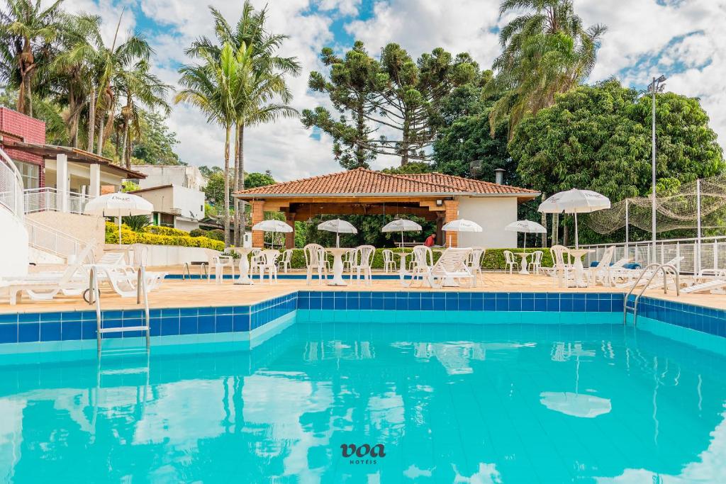 阿瓜斯迪林多亚VOA Plazza Hotel的度假村的游泳池,配有椅子和遮阳伞