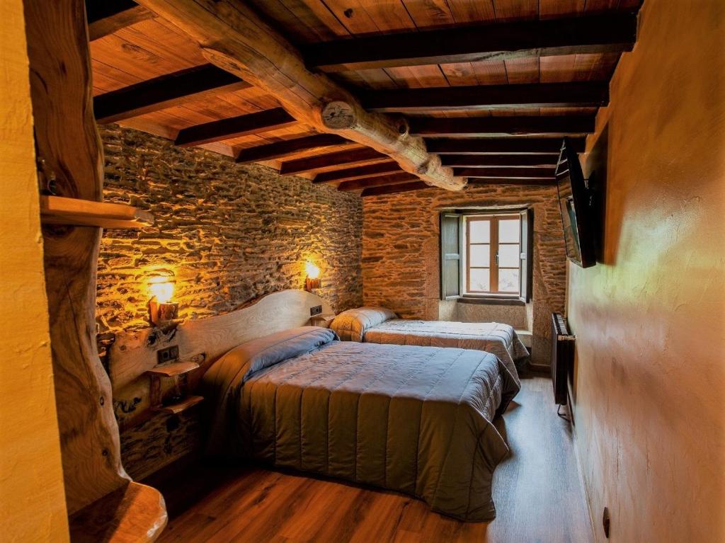 庞特维德拉Fogar de Breogán的一间卧室设有两张床和砖墙