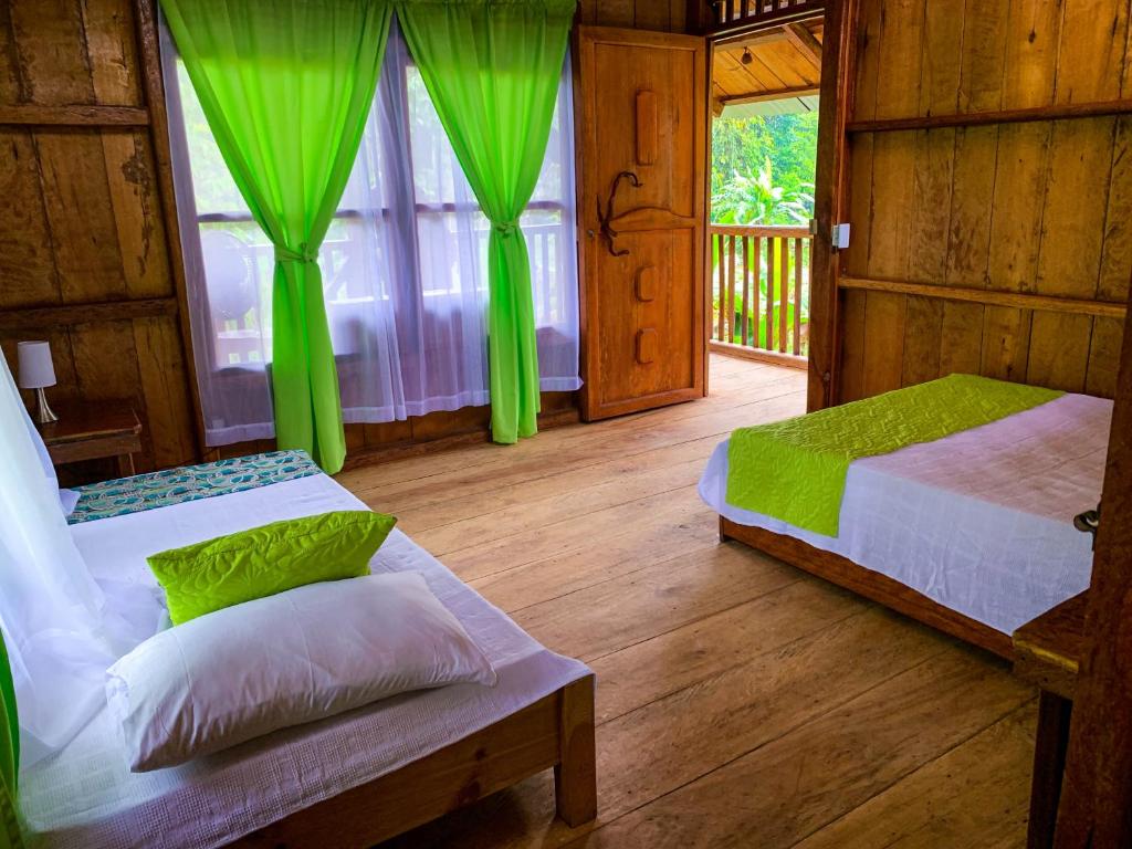 San CiprianoMama Yeya raíces的绿窗帘间内的两张床
