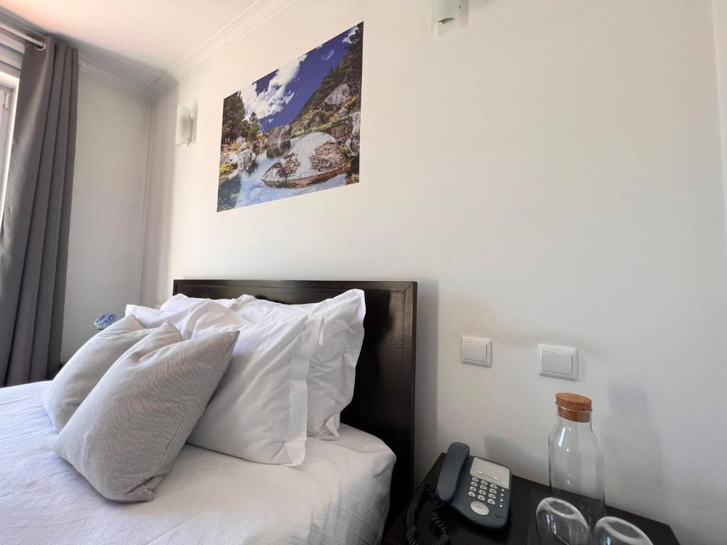 曼泰加什Vale do Zêzere Hotel的卧室配有带白色枕头的床和电话
