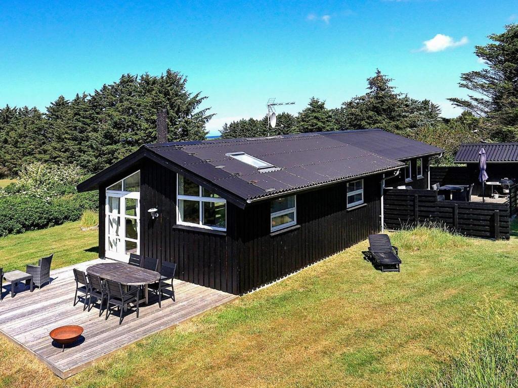 希茨海尔斯6 person holiday home in Hirtshals的黑色房子,设有野餐桌和甲板
