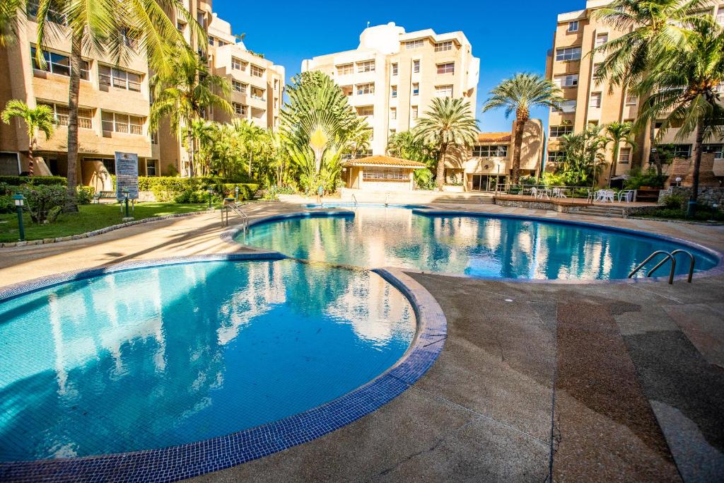 PampatarSerena apartamento vacacional的一座棕榈树和建筑的大型游泳池