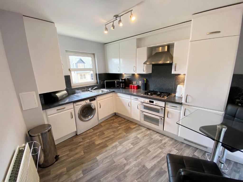 福尔柯克NEW Super 2 Bedroom Flat in Falkirk的厨房配有白色橱柜、洗衣机和烘干机