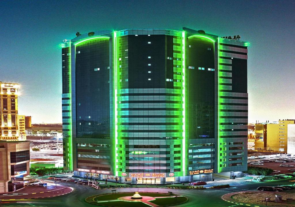 阿吉曼Alain Hotel Ajman的一座绿灯环绕的大型建筑
