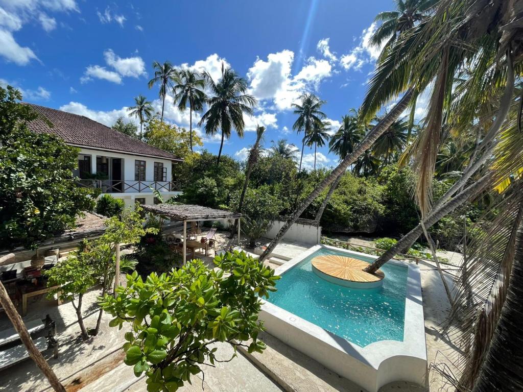 布韦朱KIMA Serviced Beach House & Suites的一座别墅的形象,别墅内设有一个游泳池和棕榈树