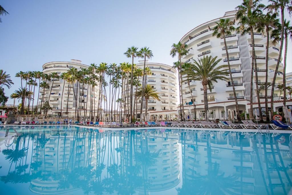 英格兰海滩思维德威基基酒店的一座大型游泳池,在一座建筑前种有棕榈树