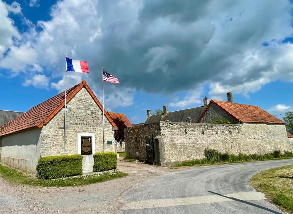 Saint-Côme-du-MontLa Ferme Delaunay的一座古老的石头建筑,上面有两面旗帜
