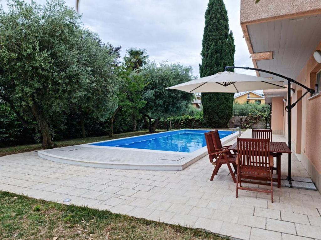奥托纳Relais tra gli Ulivi的一个带遮阳伞和桌椅的游泳池