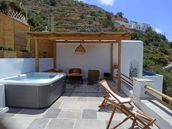 阿莫尔戈斯Idothea guest house的庭院设有热水浴池、桌子和椅子。