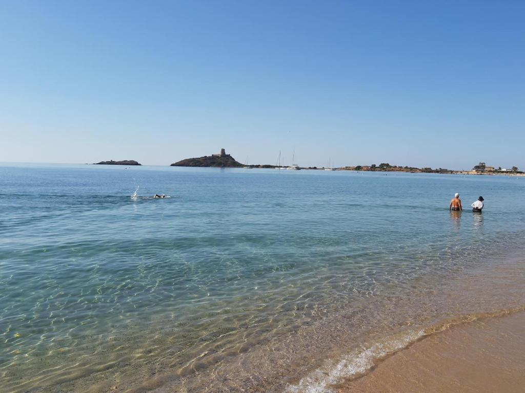 普拉A 30 metri dal mare di Nora, casa confortevole的两个人站在海滩的水面上