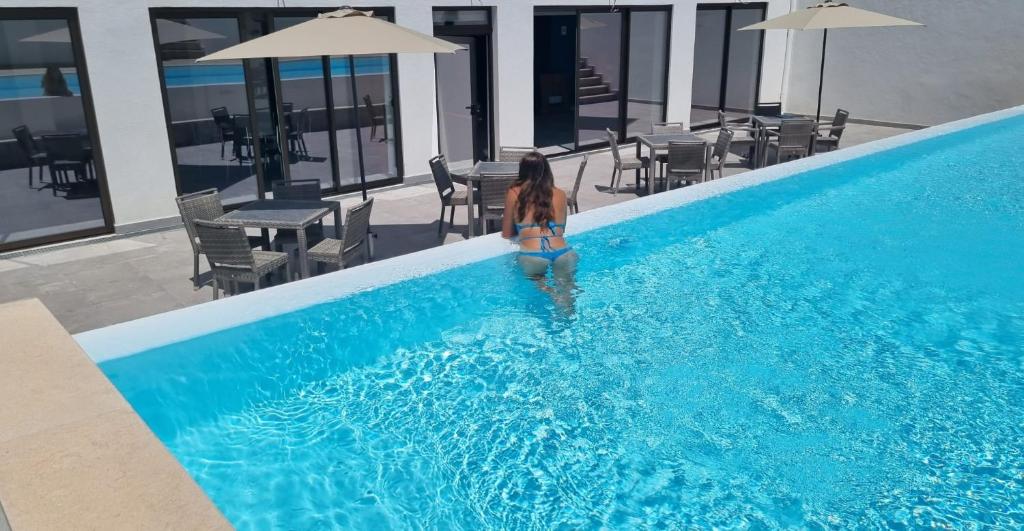 塞卡尔卡萨祖尔M&B酒店的站在游泳池里的比基尼的女人