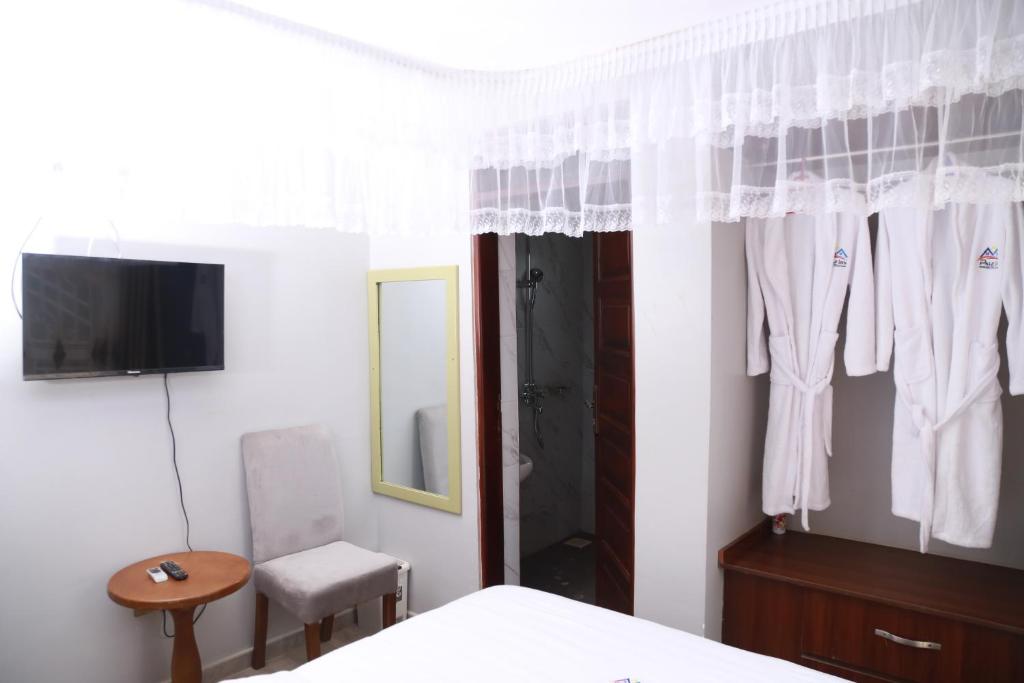 BusiaPals Inn的一间卧室配有一张床、一台电视和一面镜子