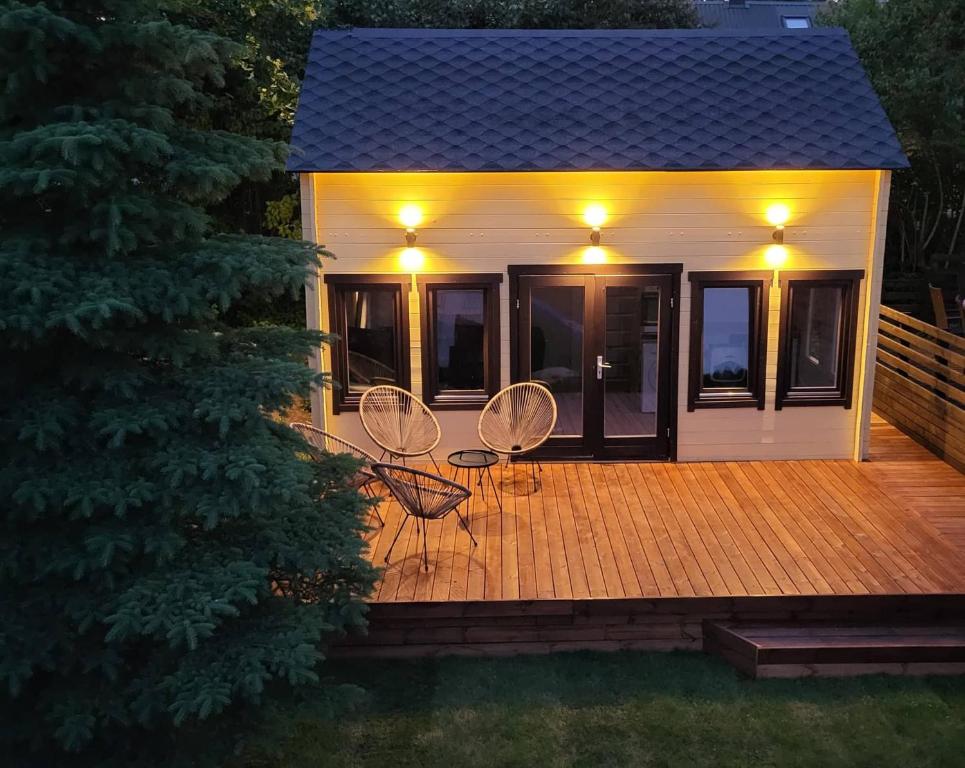 维尔扬迪Tiny house near Viljandi lake的甲板上配有两把椅子和灯的房子
