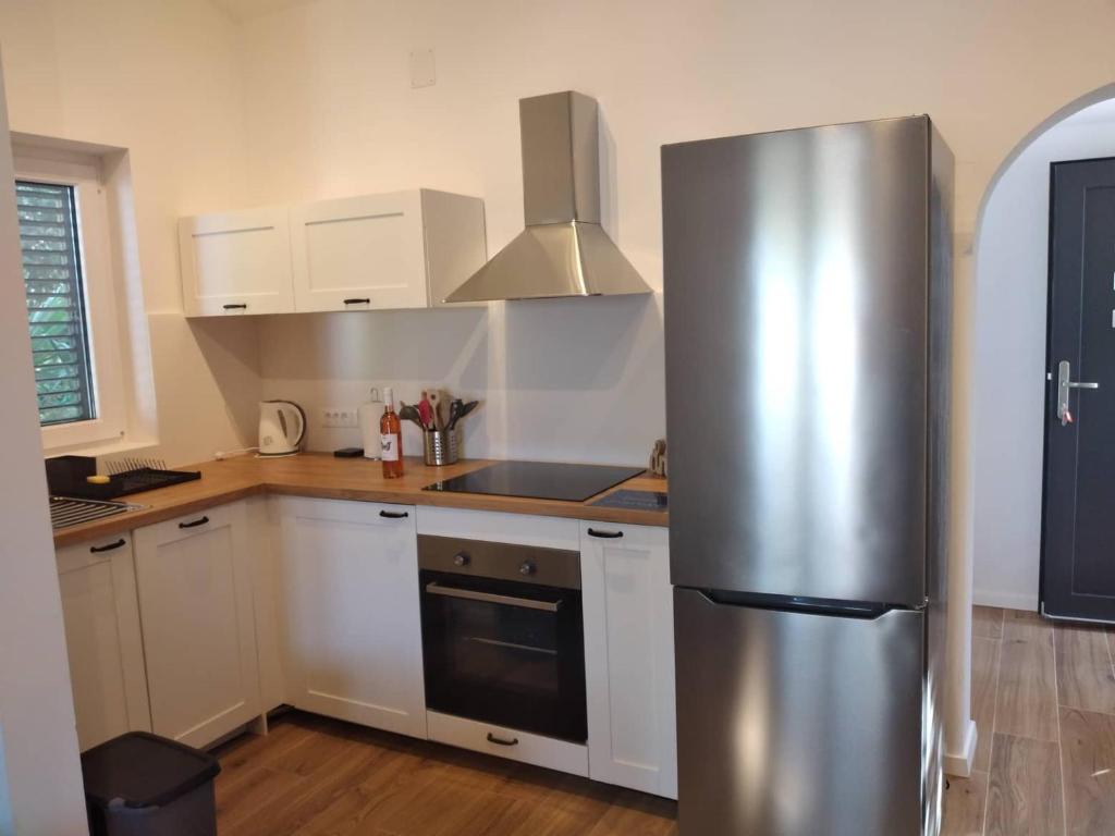 普莱曼图拉Apartmani LUNI的厨房配有不锈钢冰箱和白色橱柜