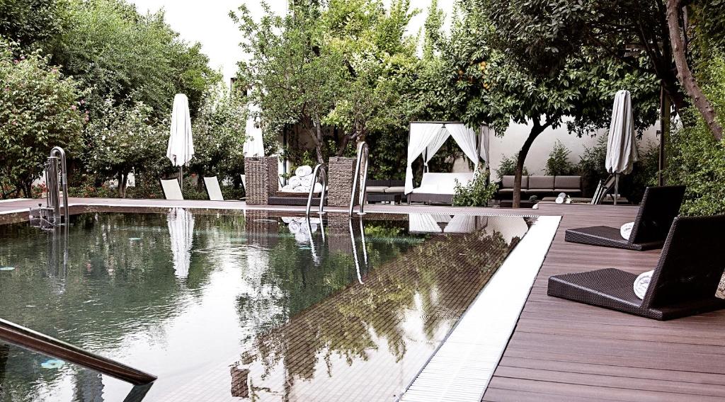 科尔多瓦Hospes Palacio del Bailio, a Member of Design Hotels的游泳池旁设有桌椅