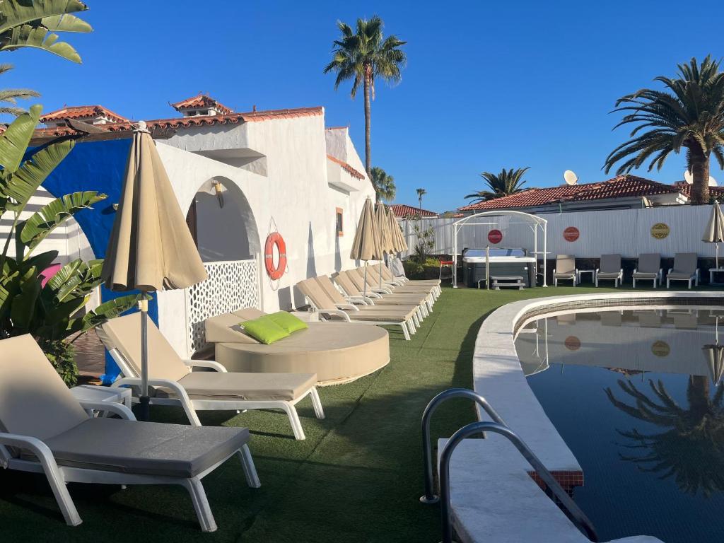 马斯帕洛马斯彩虹高尔夫别墅度假酒店，仅限男同性恋者的一组椅子和遮阳伞,位于游泳池旁