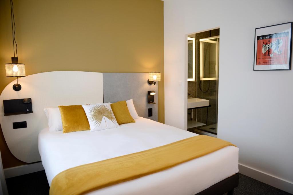里昂Hôtel Villa Berlioz的配有金色枕头的大型白色床的酒店客房