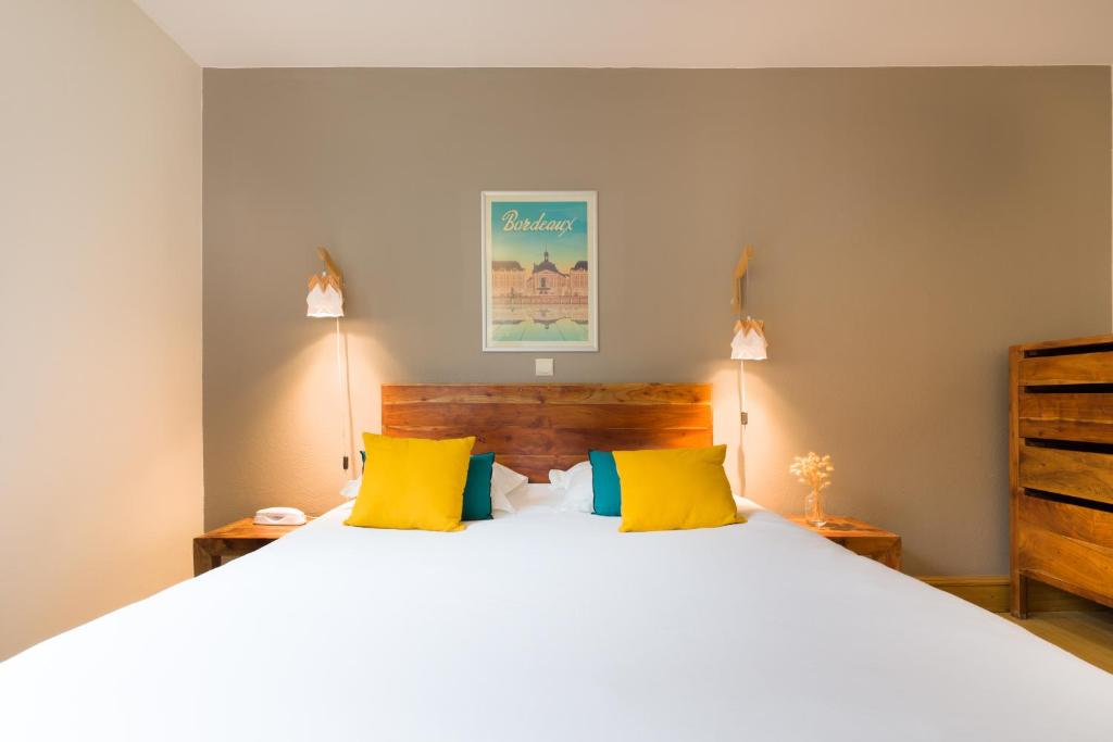 波尔多波尔多中心维多利亚花园酒店的卧室配有一张带黄色枕头的大型白色床。
