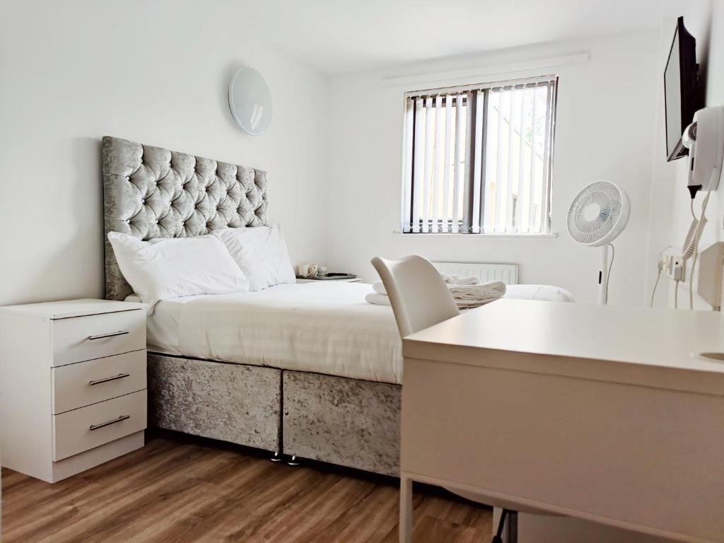 布雷得佛Accommodation Bradford的白色卧室配有一张大床和一张书桌