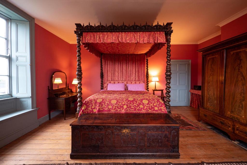 斯肯索普Sawcliffe Manor Country House with Spa, Free Parking, Catering, Self Checkin, Farmstay的一间卧室设有天蓬床和红色墙壁