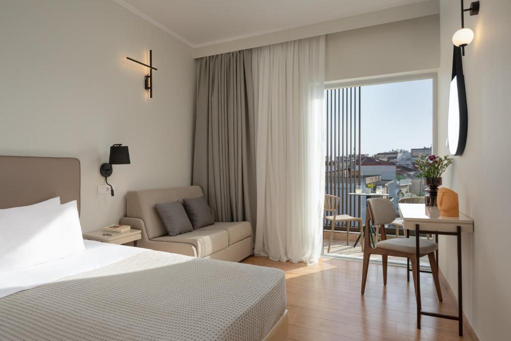 普雷韦扎Preveza City Comfort Hotel的一间卧室配有一张床、一张桌子和一张沙发
