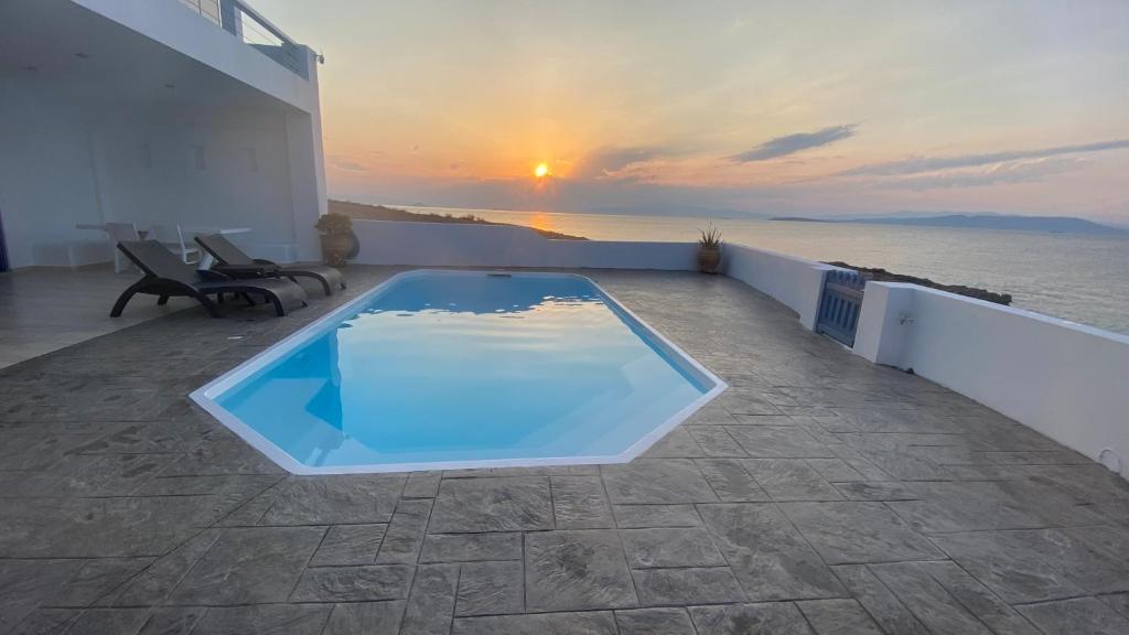 ÁyioiNV Pool Villa的一座享有日落美景的房屋屋顶上的游泳池