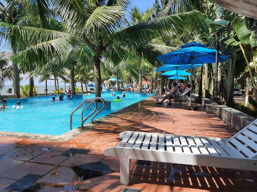 清化Eureka Resort, Hai Tien Beach的棕榈树度假村内有人的游泳池