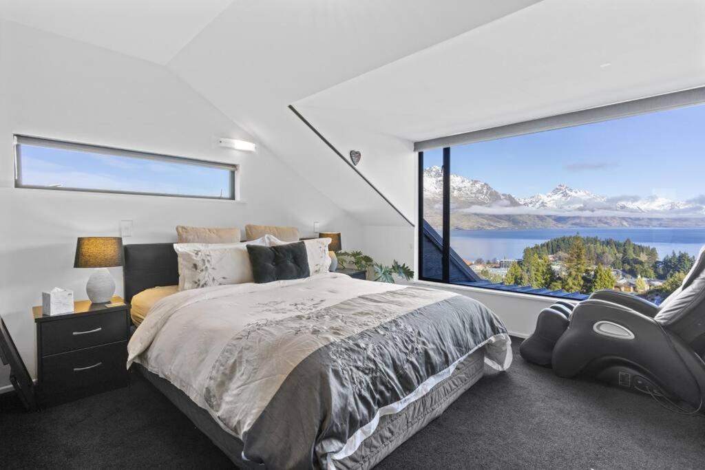 皇后镇Awesome Studio - Amazing Mountain & Lake Views的卧室设有大窗户、一张床和一把椅子