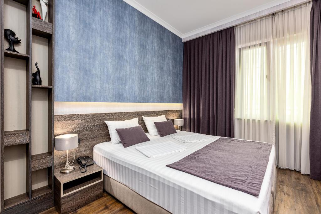 第比利斯Kope Palace的一间卧室设有一张大床和蓝色的墙壁