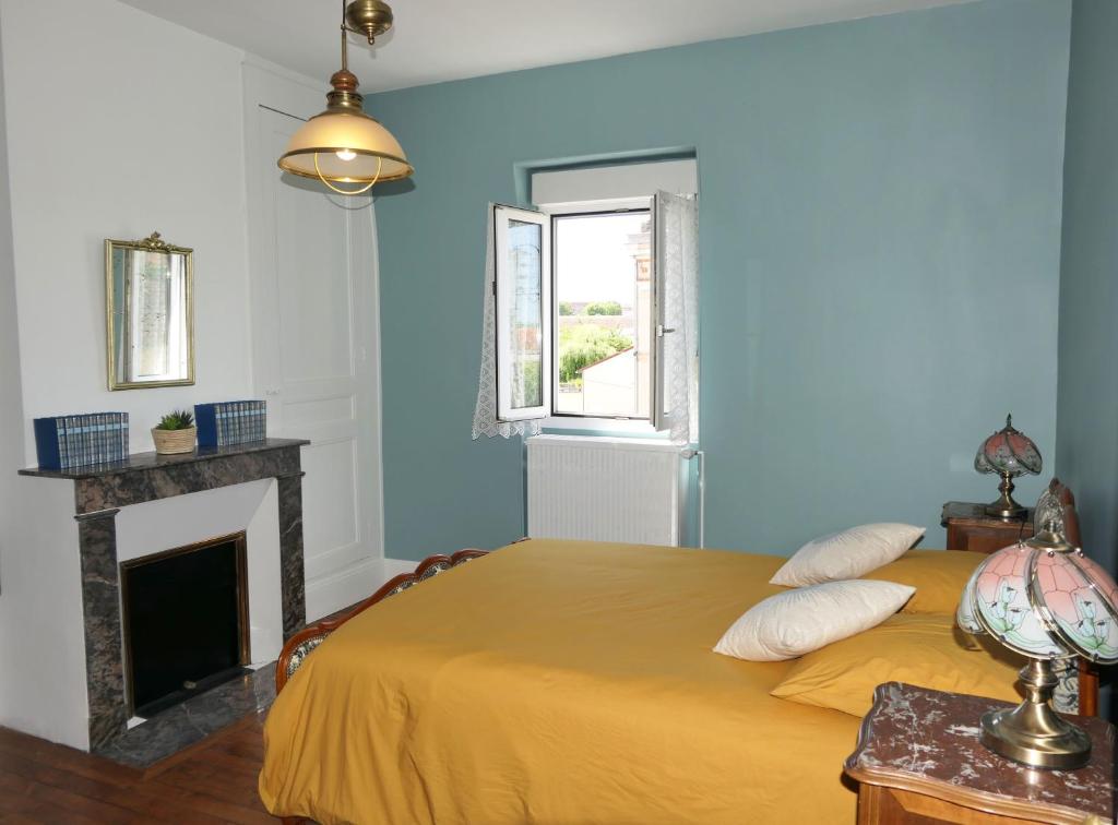 欧塞尔La p'tite bourgeoise Auxerroise, demeure de charme.的蓝色卧室设有一张床和一个壁炉